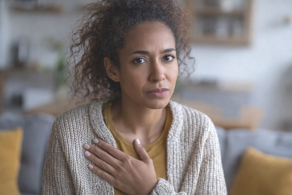 fibroid symptoms woman hand on heart